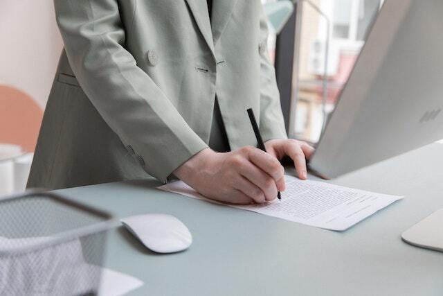 signing a contract at a desk in front of a computer